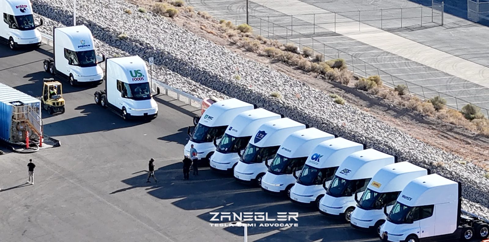 Camions Tesla Semi avec logos clients alignés à l'usine du Nevada